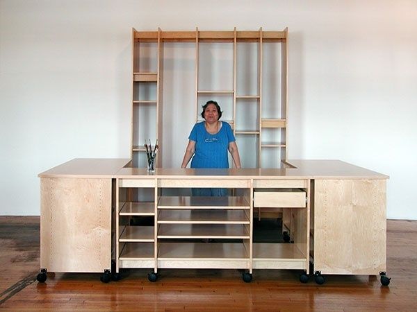 Modular wooden studio worktable with shelves and a person standing behind it