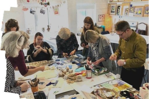 People collaboratively making art around a shared workshop table