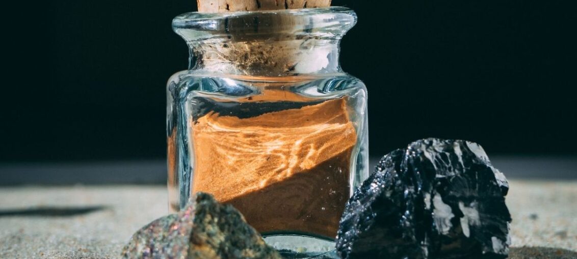 Glass jar of ochre earth pigment with a cork stopper and stones