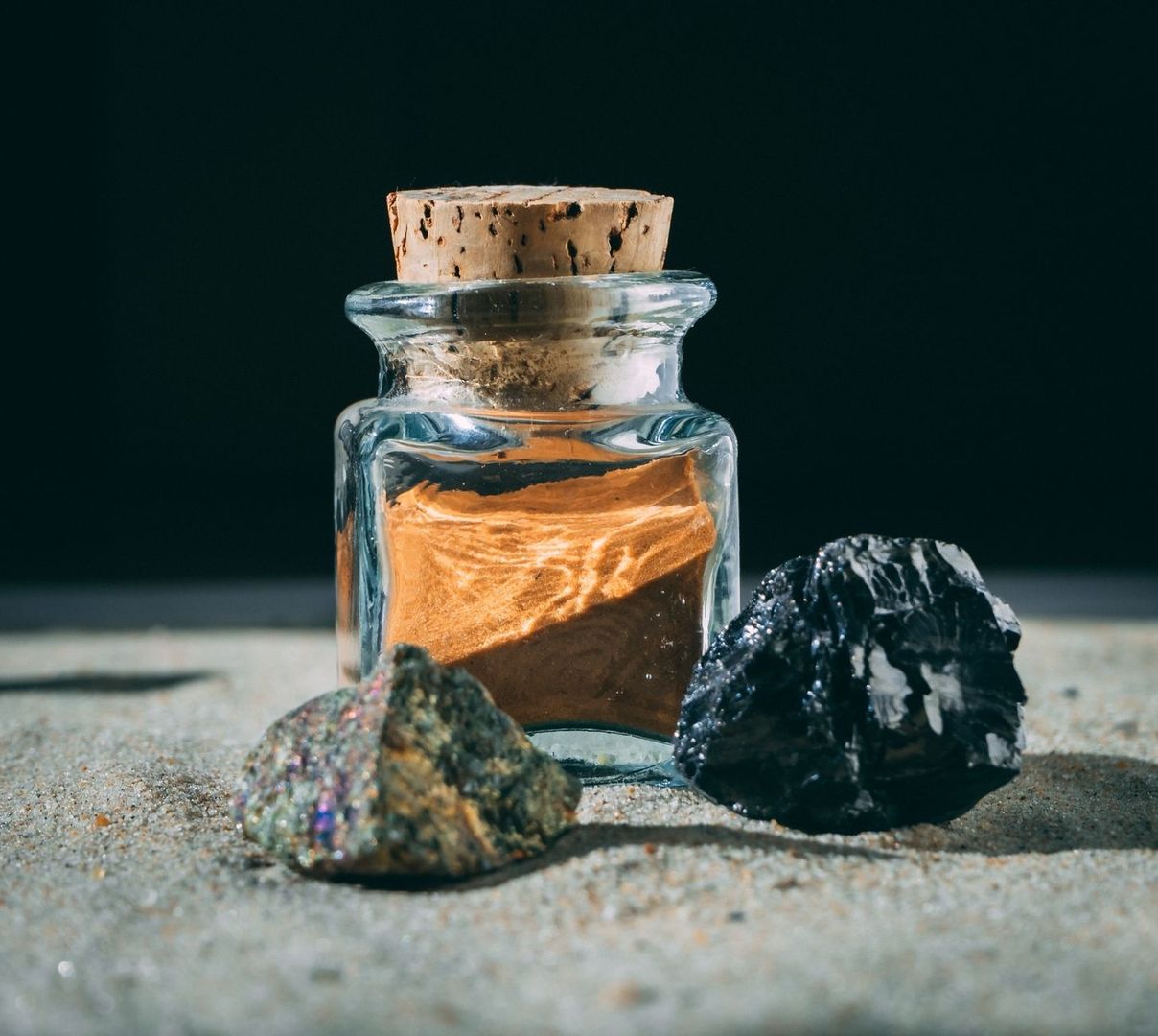 Glass jar of ochre earth pigment with a cork stopper and stones
